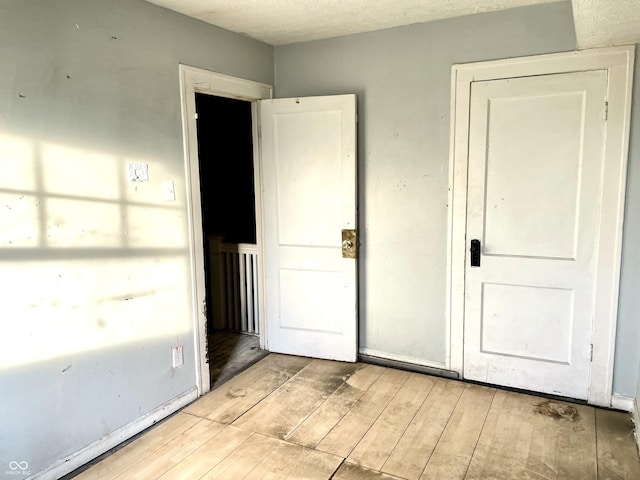 unfurnished room with a textured ceiling and light wood-type flooring