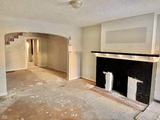 unfurnished living room featuring a brick fireplace and a textured ceiling