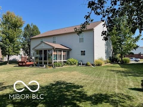 back of house with a lawn, a wooden deck, and a sunroom