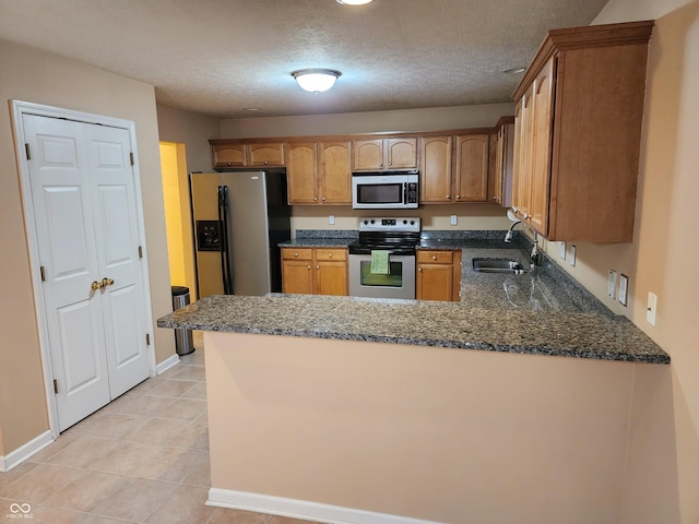 kitchen featuring kitchen peninsula, a textured ceiling, stainless steel appliances, and sink