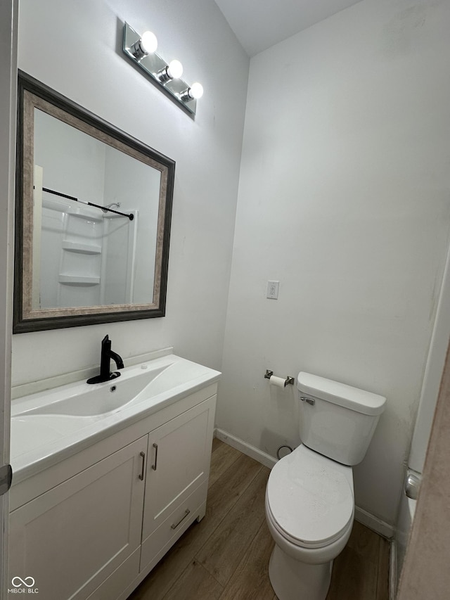 bathroom with toilet, vanity, and hardwood / wood-style flooring