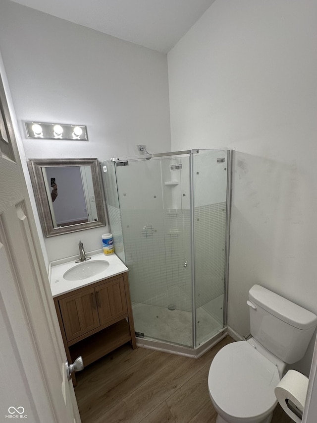 bathroom featuring wood-type flooring, vanity, toilet, and a shower with door