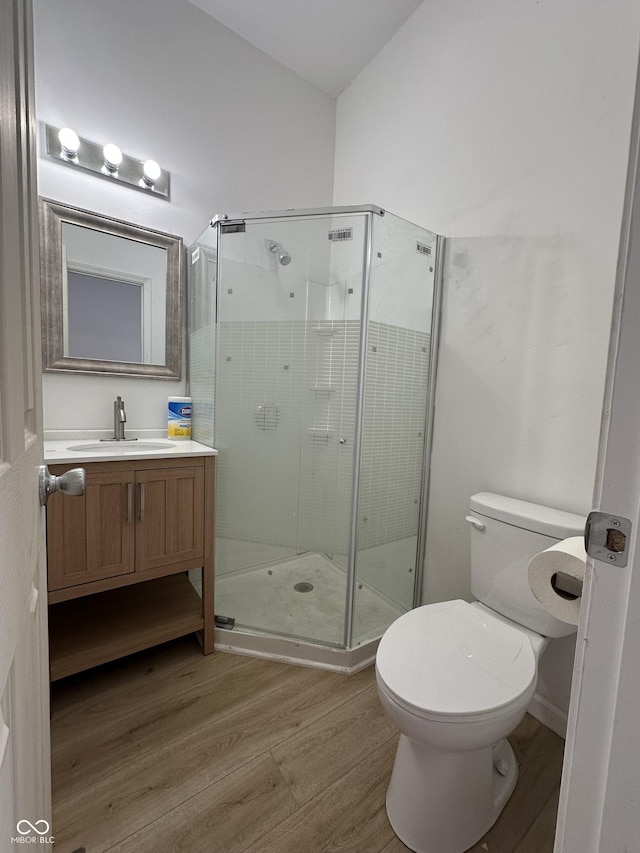 bathroom featuring hardwood / wood-style floors, vanity, toilet, and an enclosed shower