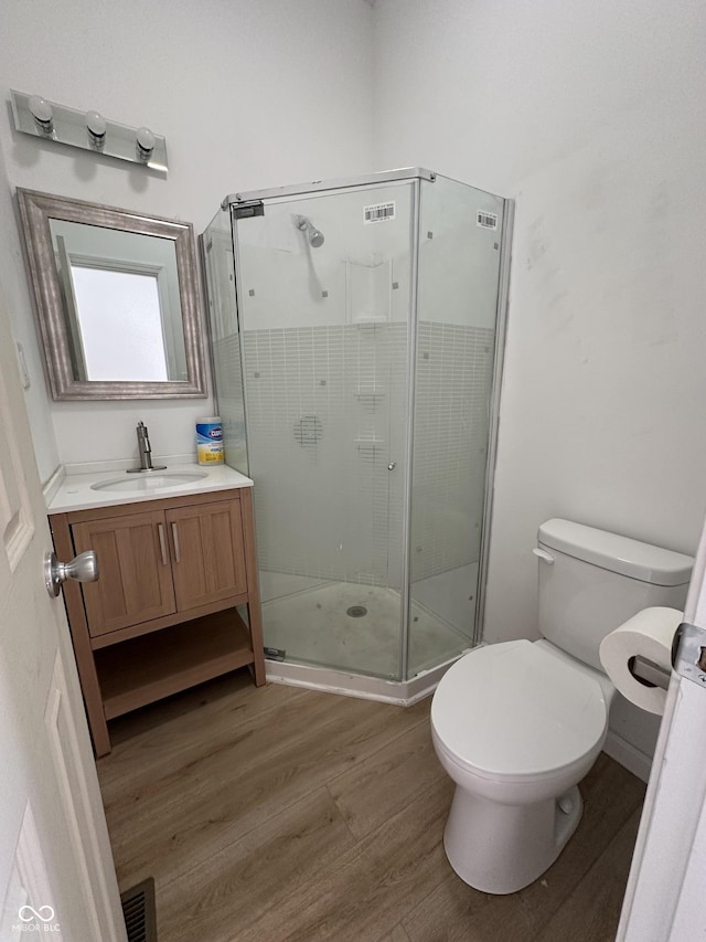 bathroom with vanity, toilet, a shower with shower door, and wood-type flooring