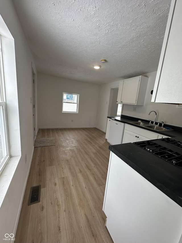 kitchen featuring white cabinetry, sink, a textured ceiling, and light wood-type flooring