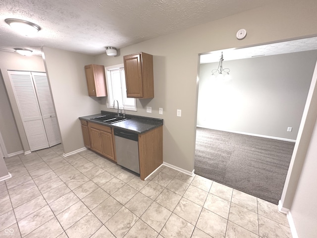 kitchen with stainless steel dishwasher, sink, hanging light fixtures, and a textured ceiling