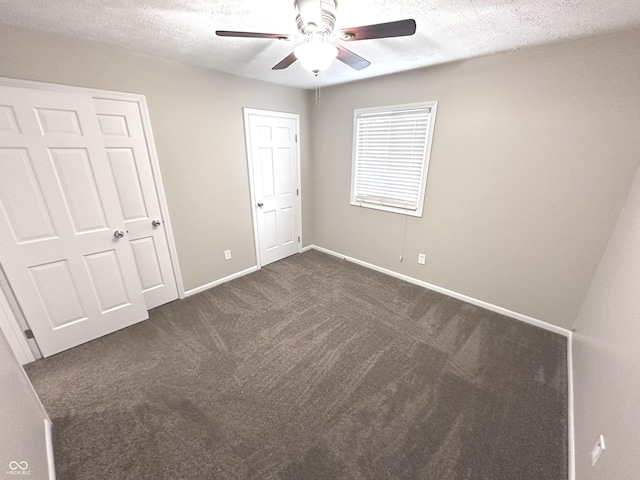 unfurnished bedroom with ceiling fan, dark carpet, and a textured ceiling