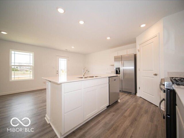 6618 Sulgrove Pl, Indianapolis, IN 46221 - kitchen with dark wood finished floors, a center island with sink, a sink, white cabinets, and appliances with stainless steel finishes