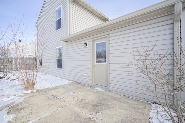 snow covered rear of property with a patio area