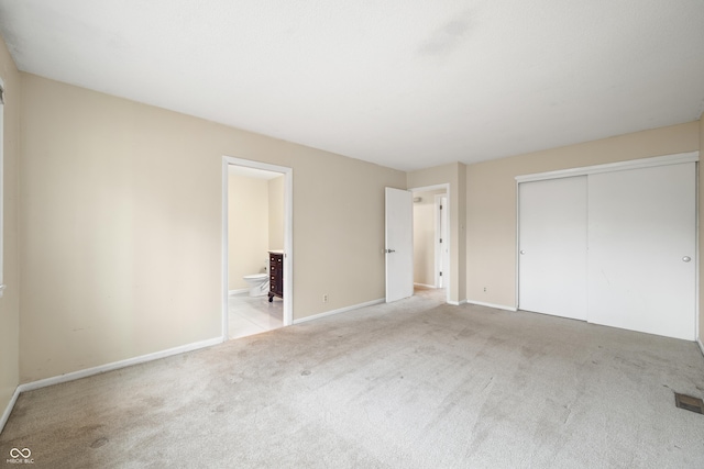 unfurnished bedroom featuring carpet, a closet, visible vents, connected bathroom, and baseboards