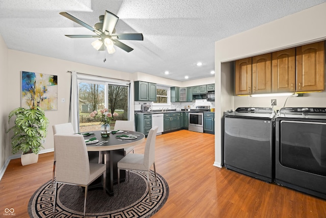 dining area featuring a textured ceiling, ceiling fan, washing machine and dryer, baseboards, and light wood-style floors