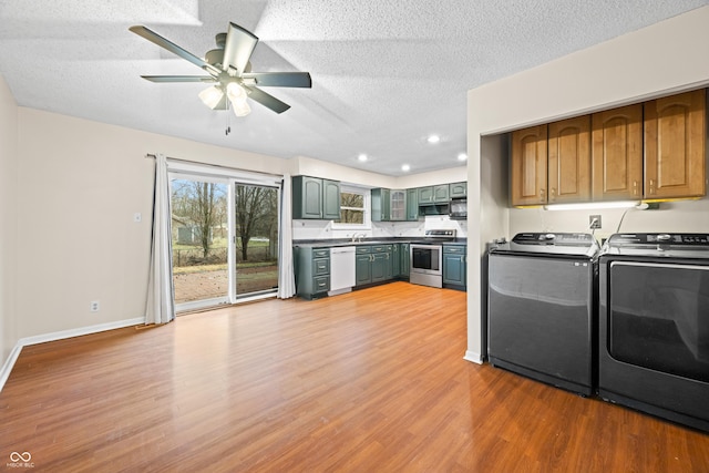 clothes washing area featuring a textured ceiling, light wood-type flooring, laundry area, independent washer and dryer, and baseboards