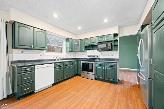 kitchen with green cabinets, stainless steel appliances, and a sink