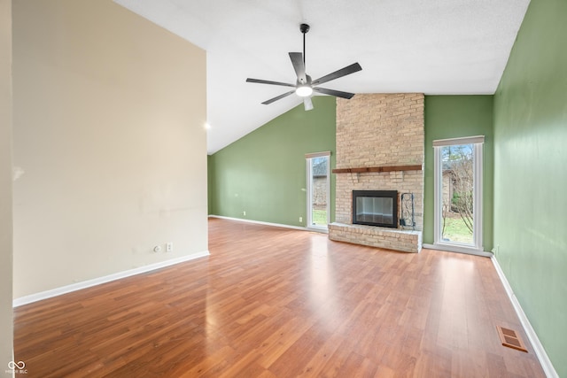 unfurnished living room featuring visible vents, baseboards, a ceiling fan, wood finished floors, and a brick fireplace