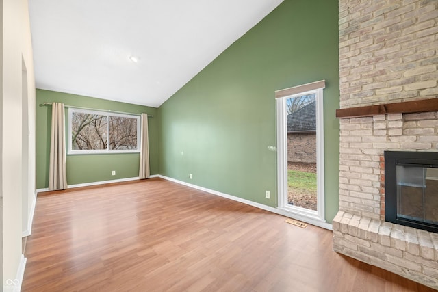 unfurnished living room with high vaulted ceiling, a fireplace, baseboards, and wood finished floors