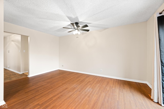 empty room featuring a textured ceiling, wood finished floors, a ceiling fan, and baseboards