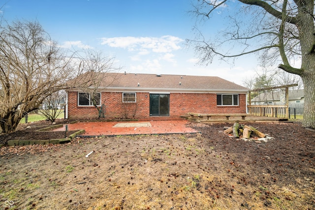 rear view of house with a patio area, fence, and brick siding