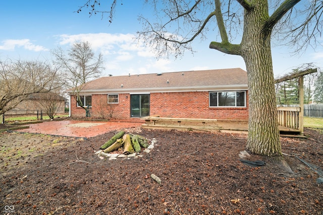 back of house featuring brick siding, roof with shingles, a patio area, and fence