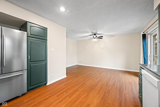 interior space with light wood-style flooring, baseboards, ceiling fan, and a textured ceiling