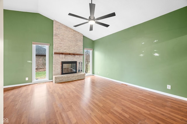 unfurnished living room featuring high vaulted ceiling, a fireplace, wood finished floors, and baseboards