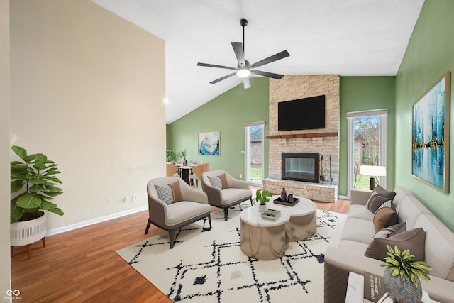 living room with baseboards, ceiling fan, wood finished floors, vaulted ceiling, and a fireplace