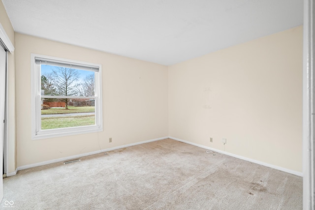 empty room featuring carpet flooring, visible vents, and baseboards