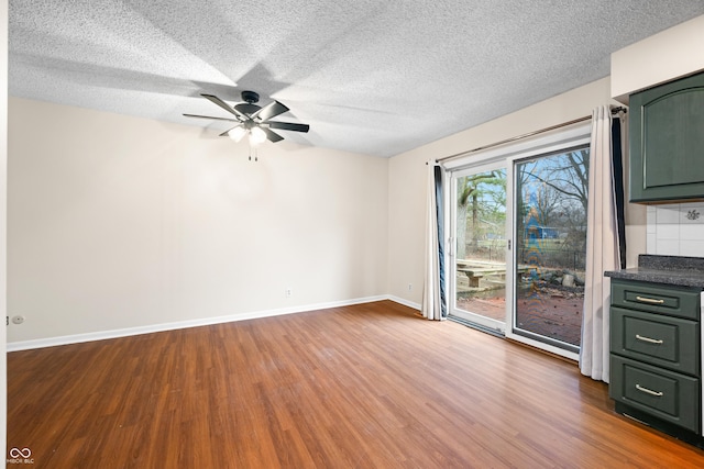 interior space featuring ceiling fan, dark wood-type flooring, a textured ceiling, and baseboards