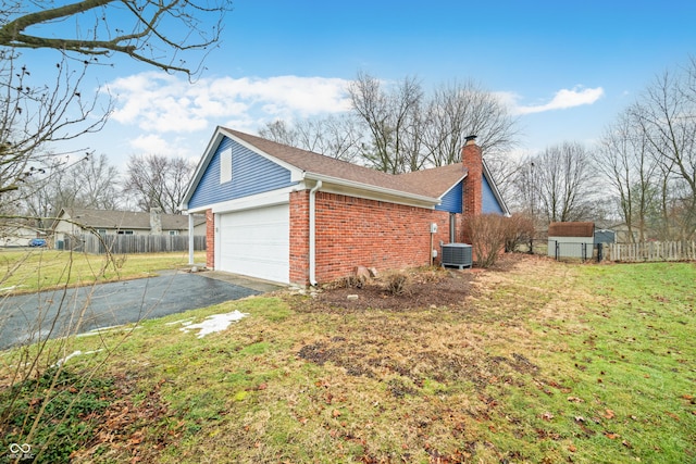 view of side of property with driveway, a chimney, fence, central AC, and brick siding