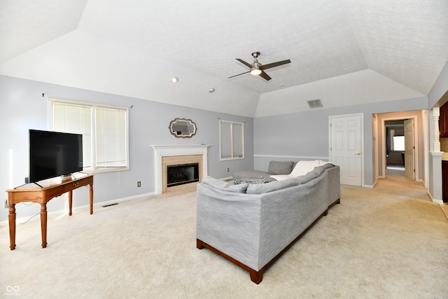 living room featuring vaulted ceiling, a textured ceiling, ceiling fan, and light carpet