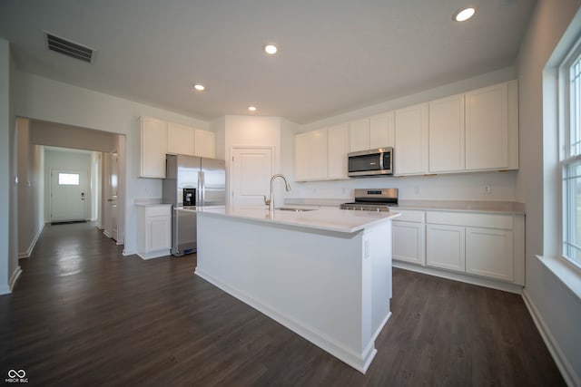 kitchen featuring dark wood-type flooring, sink, white cabinetry, an island with sink, and stainless steel appliances