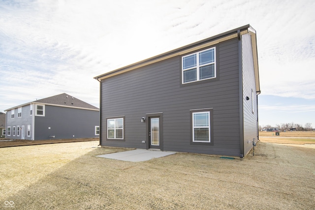 rear view of house featuring a lawn and a patio