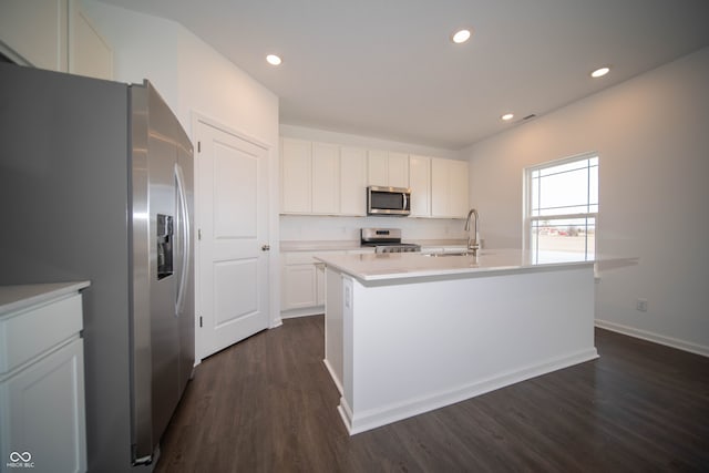 kitchen with stainless steel appliances, white cabinetry, sink, and a center island with sink