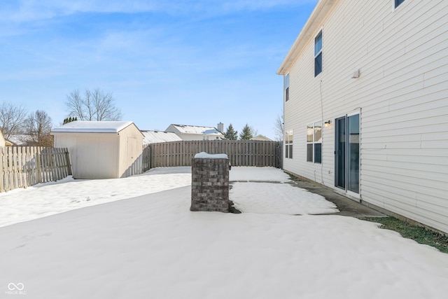 yard layered in snow featuring a storage shed