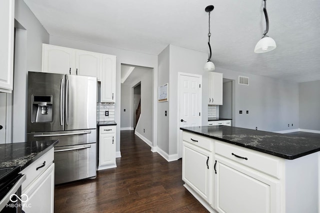 kitchen with appliances with stainless steel finishes, decorative light fixtures, white cabinetry, dark stone countertops, and backsplash