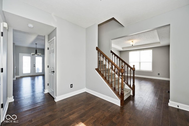 stairway featuring a notable chandelier, a tray ceiling, and hardwood / wood-style floors