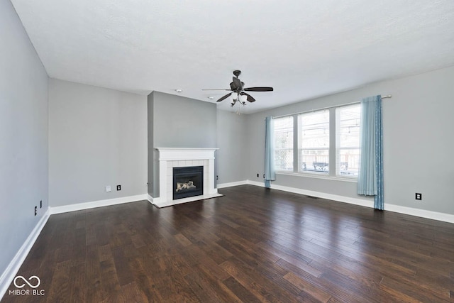 unfurnished living room featuring ceiling fan, dark wood-type flooring, a textured ceiling, and a fireplace