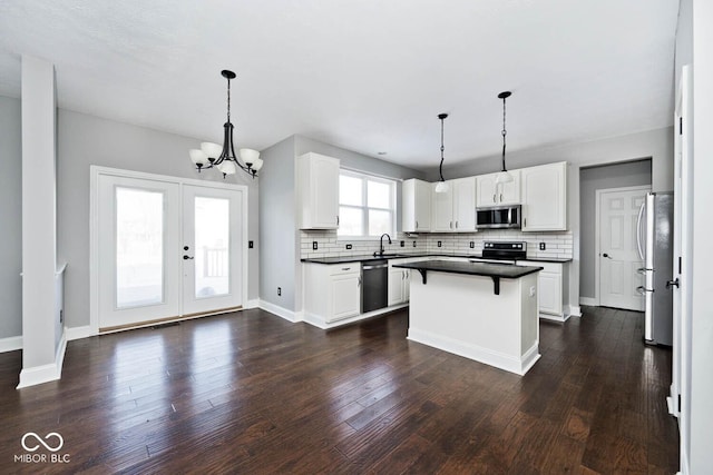 kitchen with a center island, pendant lighting, stainless steel appliances, and white cabinetry