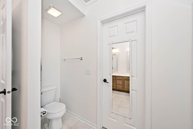 bathroom with toilet, vanity, and tile patterned flooring