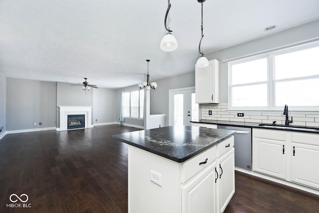 kitchen with decorative light fixtures, a center island, stainless steel dishwasher, sink, and white cabinets