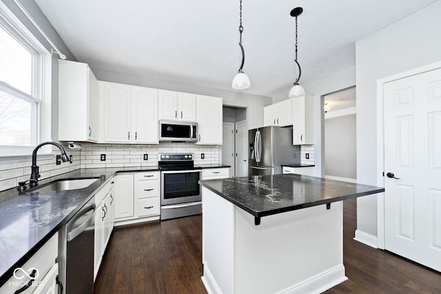 kitchen with stainless steel appliances, a kitchen breakfast bar, a kitchen island, white cabinets, and sink