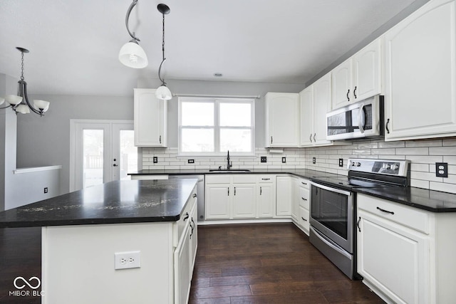 kitchen with stainless steel appliances, hanging light fixtures, a kitchen island, white cabinets, and sink