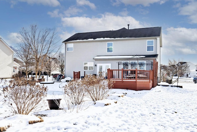 snow covered back of property featuring a deck