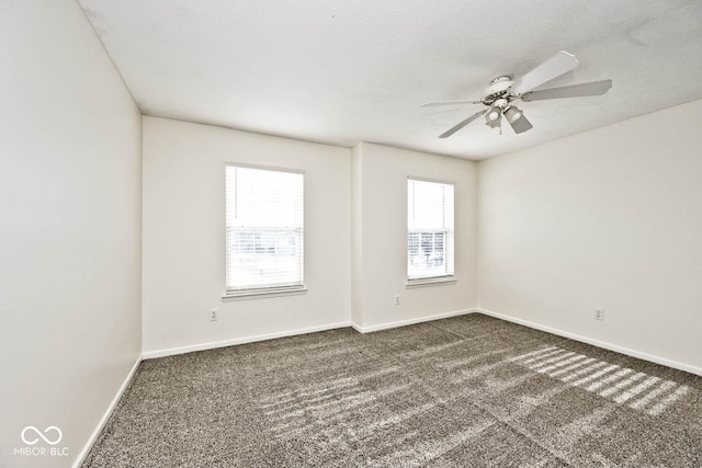 empty room featuring ceiling fan and dark carpet