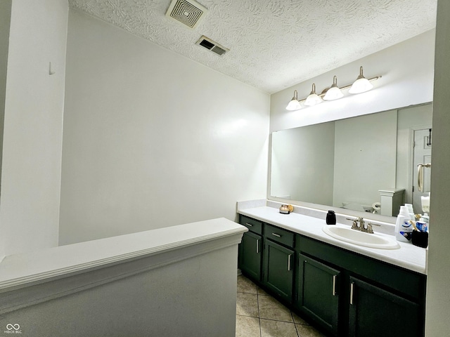 bathroom with tile patterned flooring, vanity, a textured ceiling, and toilet