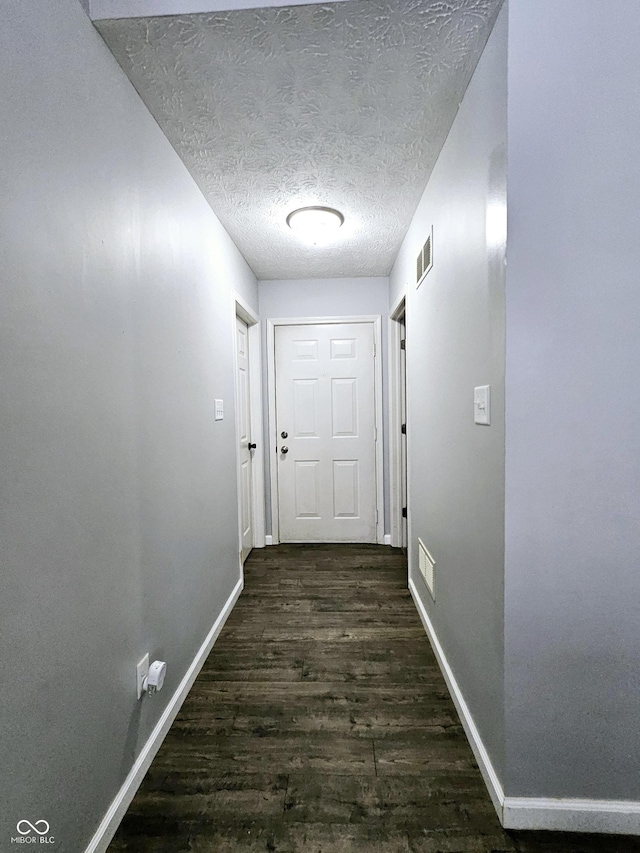 hallway with dark wood-type flooring and a textured ceiling