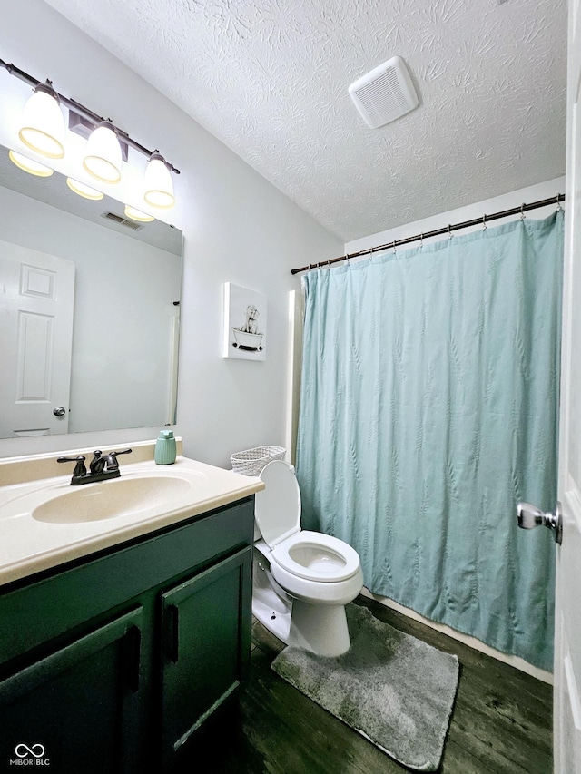 bathroom with hardwood / wood-style floors, vanity, a textured ceiling, and toilet