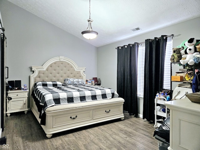 bedroom with hardwood / wood-style flooring, a textured ceiling, and vaulted ceiling