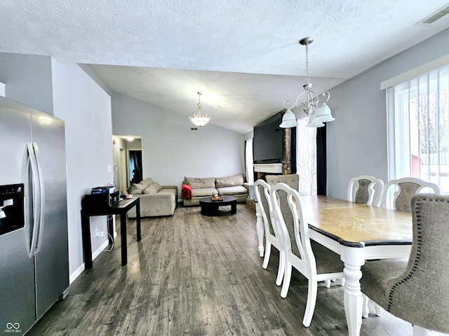 dining area featuring a textured ceiling, vaulted ceiling, an inviting chandelier, and dark hardwood / wood-style flooring