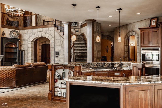 kitchen with stainless steel appliances, light stone counters, hanging light fixtures, and a notable chandelier