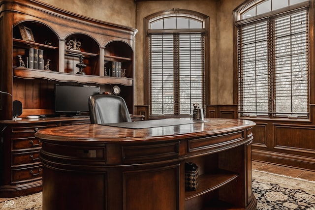 home office with a wealth of natural light, wood walls, and built in shelves